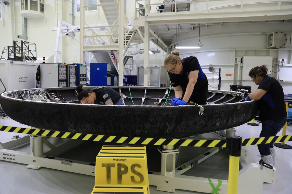 Technicians examine Orion's heat shield as part of post-flight analysis.
