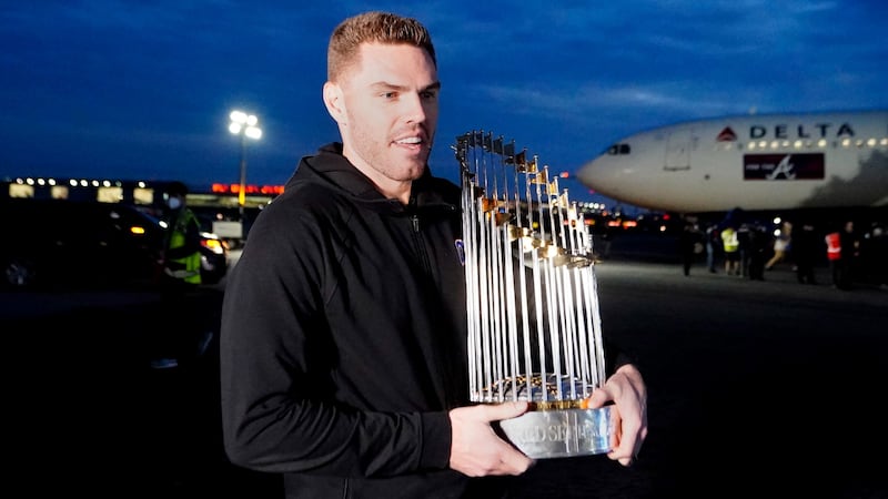 Atlanta Braves first baseman Freddie Freeman holds the trophy as he and his teammates arrive...